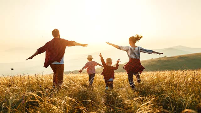 família contente a correr ao pôr-do-sol