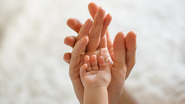 mão de adultos a segurar numa mão de bébé
